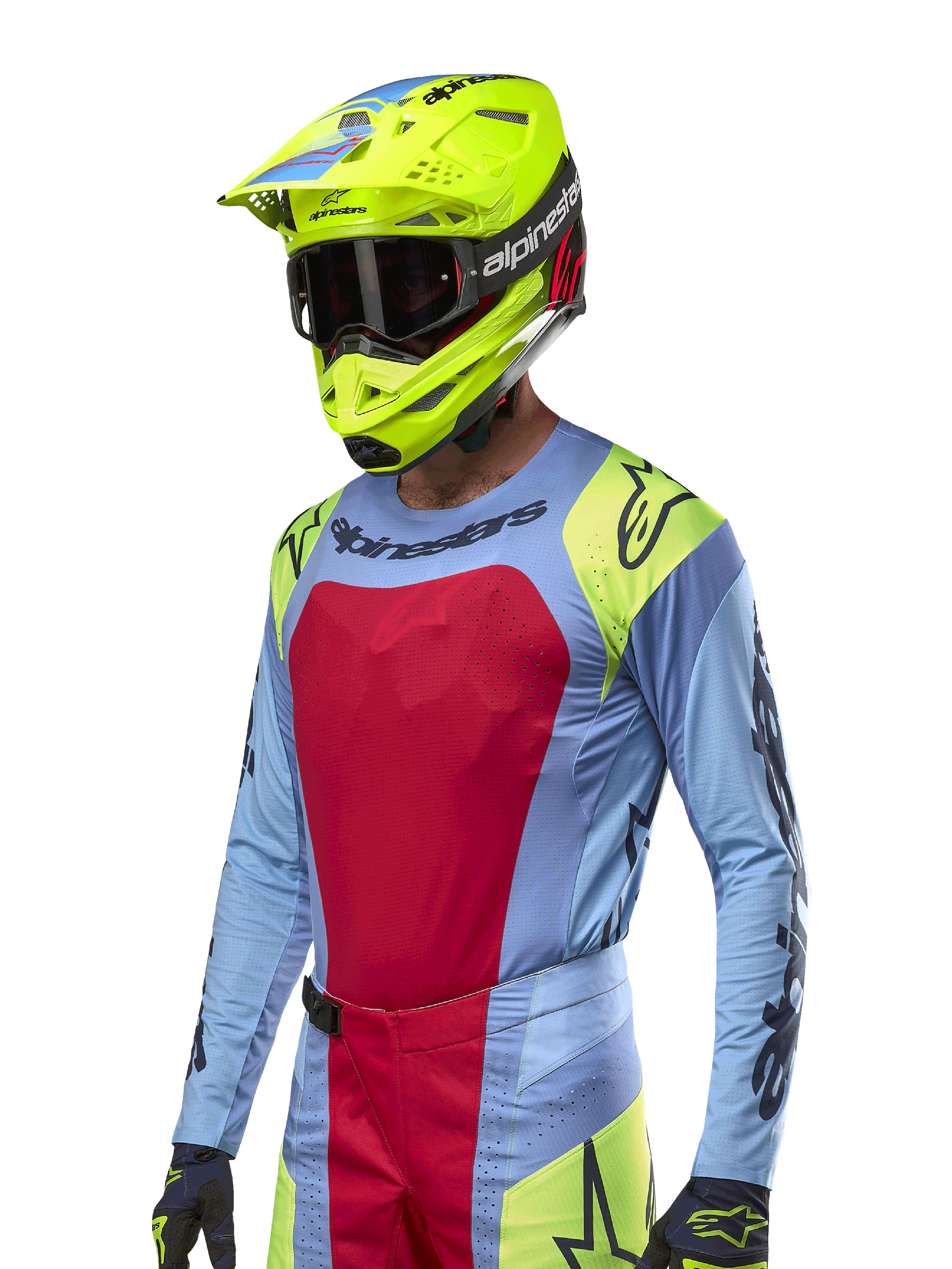 Alpinestars 2024 Techstar Ocuri trøje, motocross racingtrøje, lyseblå med røde og neongule detaljer, båret med matchende neongul hjelm og sorte goggles, med sorte Alpinestars-logoer på bryst og skuldre, atletisk race-inspireret design til off-road ydeevne