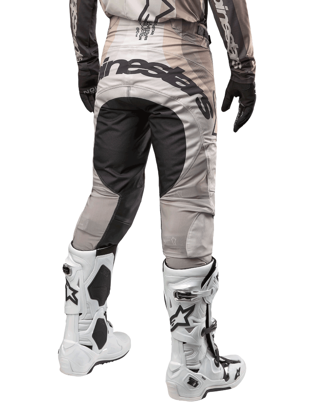 Alpinestars 2024 Techstar Pneuma bukser, motocross-bukser, Dark Sand og Iron Dust grå, set bagfra fra taljen og ned, markant sort Alpinestars-branding på sædet, båret med hvide og sorte motocross-støvler og sorte handsker, holdbart race-fit design til off-road konkurrence
