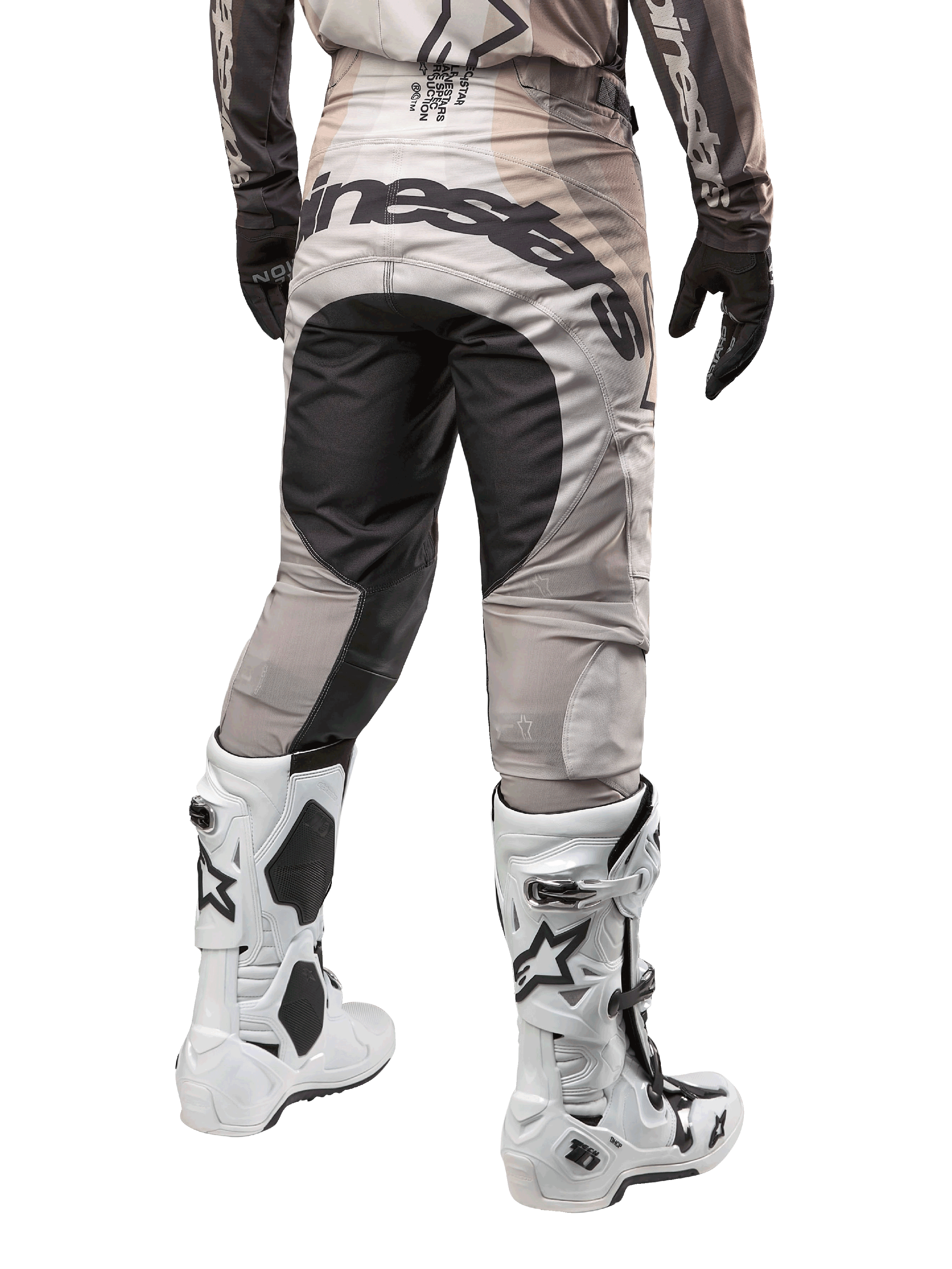 Alpinestars 2024 Techstar Pneuma bukser, motocross-bukser, Dark Sand og Iron Dust grå, set bagfra fra taljen og ned, markant sort Alpinestars-branding på sædet, båret med hvide og sorte motocross-støvler og sorte handsker, holdbart race-fit design til off-road konkurrence