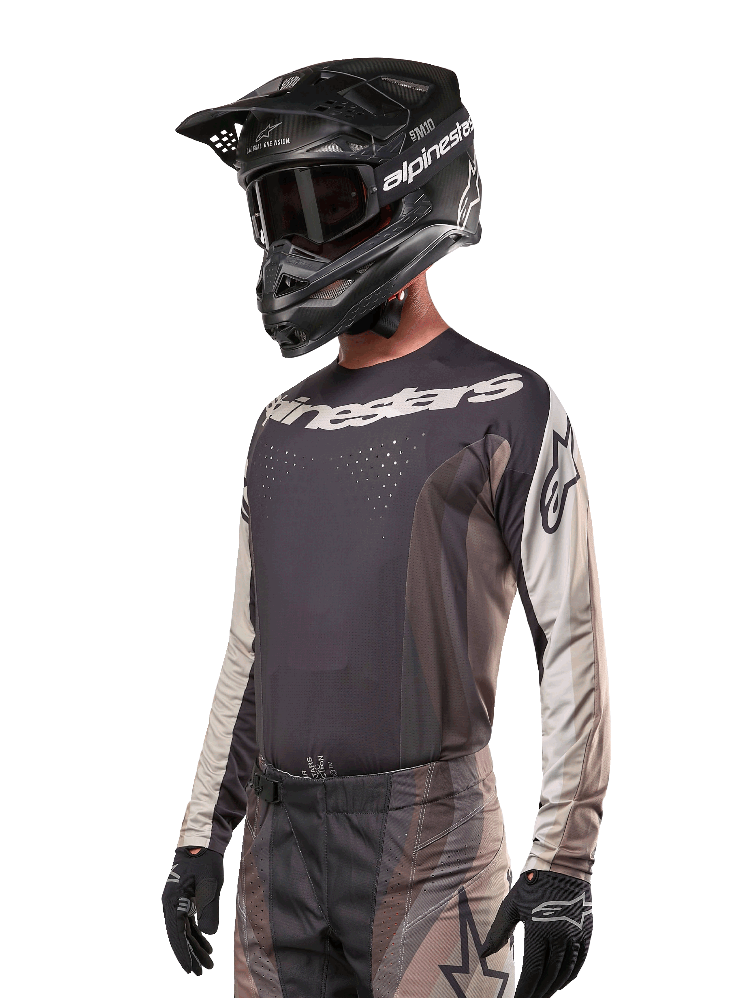 Alpinestars 2024 Techstar Pneuma trøje, motocross-racingtrøje, Dark Sand og Iron Dust Gray, langærmet performance-top med laserskårne perforeringer og hvid branding, båret med matchende bukser og sort hjelm, atletisk pasform til off-road kørsel.