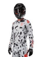 Alpinestars 2024 Techstar Rantera trøje, motocross-trøje, Haze Gray Camo med sorte abstrakte mønstre og røde detaljer, langærmet design båret med matchende sort hjelm og handsker, teknisk off-road racerudstyr
