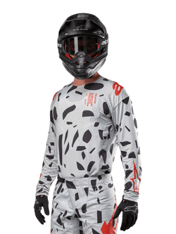 Alpinestars 2024 Techstar Rantera Jersey, Motocross Jersey, Haze Gray Camo with black abstract patterns and red accents, long-sleeve design worn with matching black helmet and gloves, technical off-road racing gear