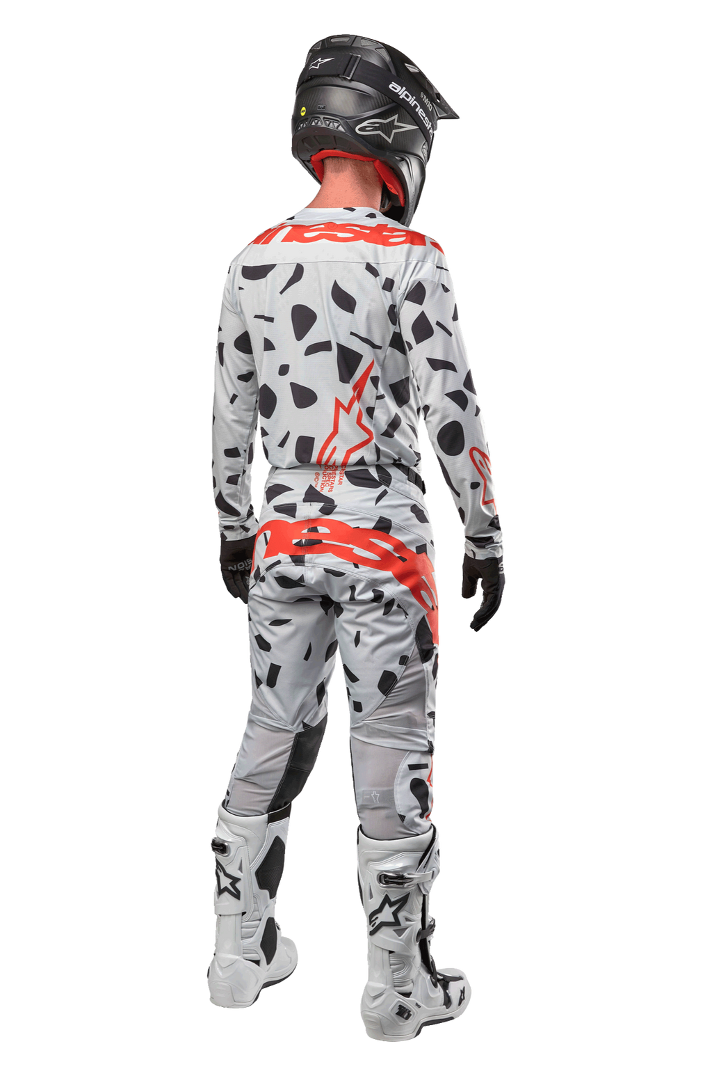 Motocrosskører set bagfra iført Alpinestars 2024 Techstar Rantera bukser, Haze Gray Camo med sorte pletter og røde logoer, matchende trøje, sort hjelm og hvide støvler, komplet off-road racerudstyr