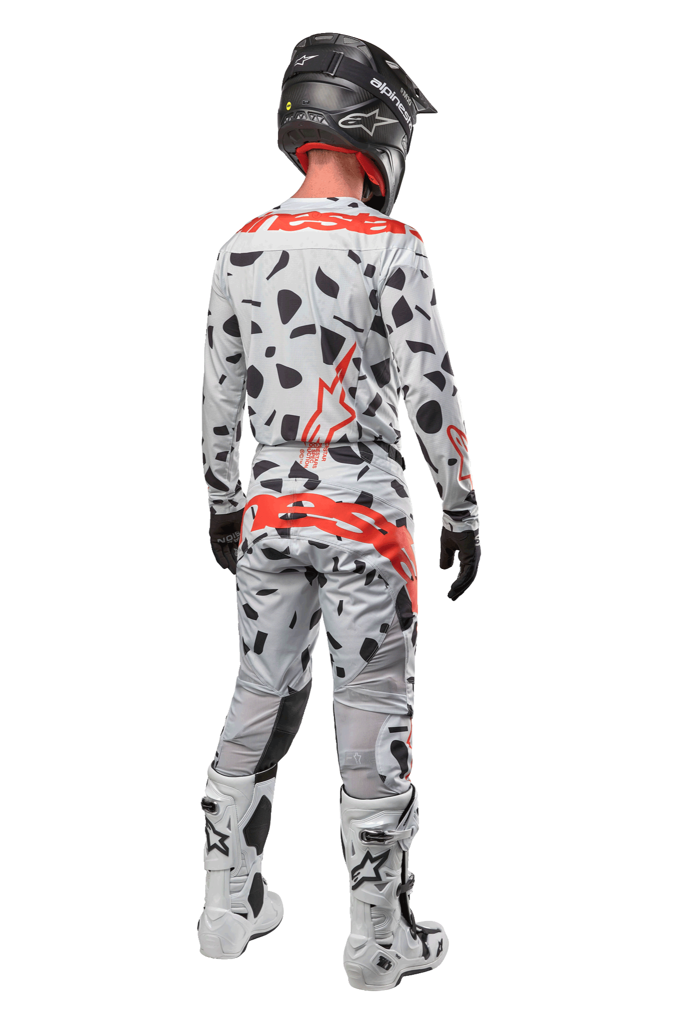 Motocrosskører set bagfra iført Alpinestars 2024 Techstar Rantera bukser, Haze Gray Camo med sorte pletter og røde logoer, matchende trøje, sort hjelm og hvide støvler, komplet off-road racerudstyr