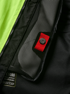 Alpinestars Tech-Air® 3 V2 System detalje, tætbillede af indvendig mesh-lomme med rød trækstrop og trykknap, stærk gul fluo-panel, sort tekstilkonstruktion med airbag-modul mærkat og lynlås