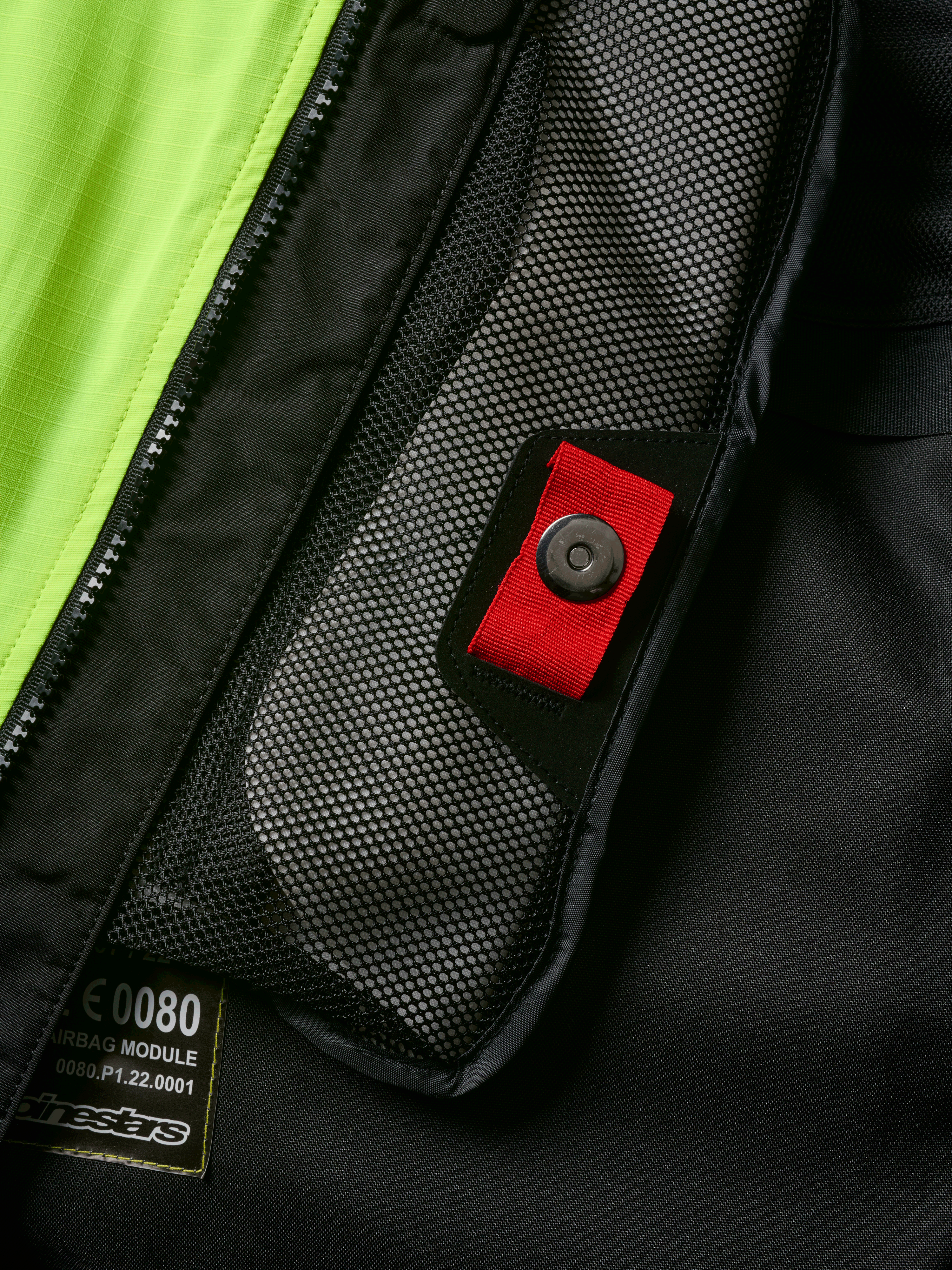 Alpinestars Tech-Air® 3 V2 System detalje, tætbillede af indvendig mesh-lomme med rød trækstrop og trykknap, stærk gul fluo-panel, sort tekstilkonstruktion med airbag-modul mærkat og lynlås