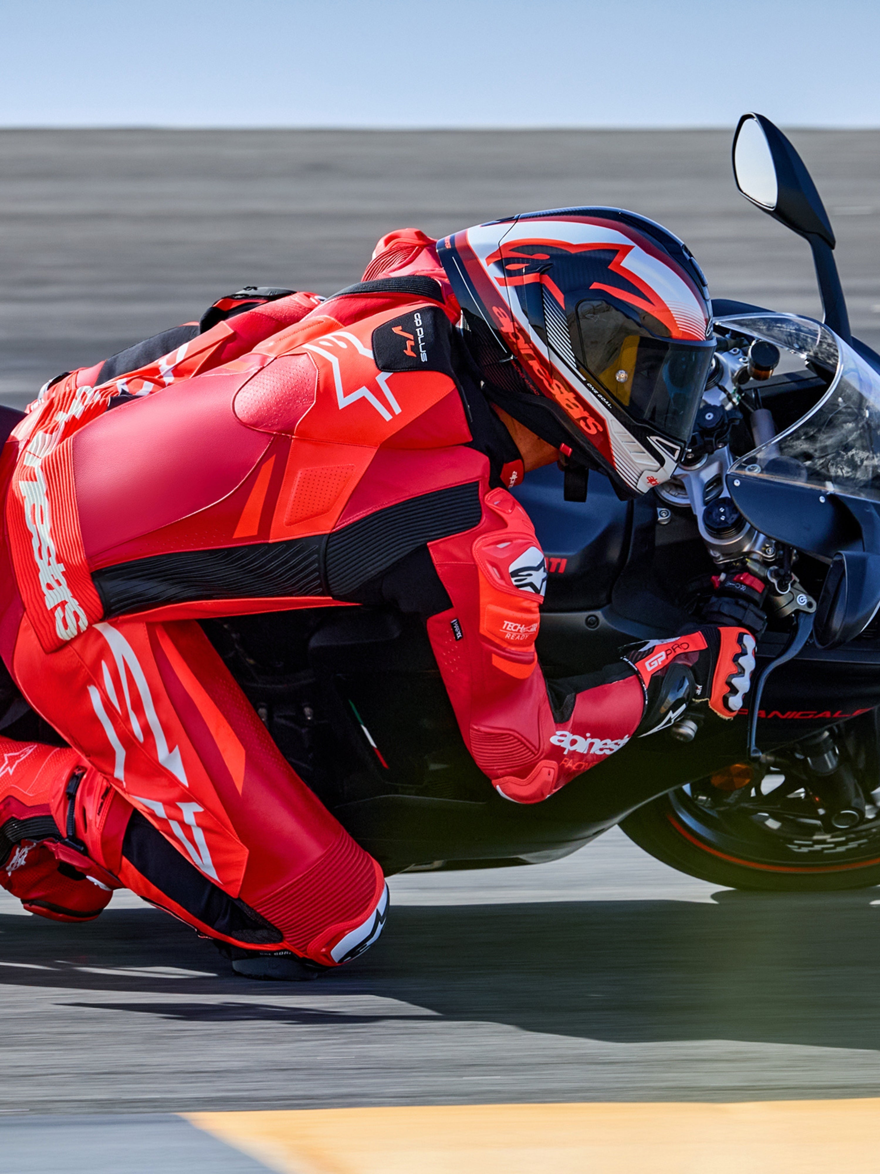 Alpinestars GP Plus V4 Sprint læderdragt 1-stk, racing, rød og hvid, Tech-Air® klar, motorcyklist i sving på racerbane.