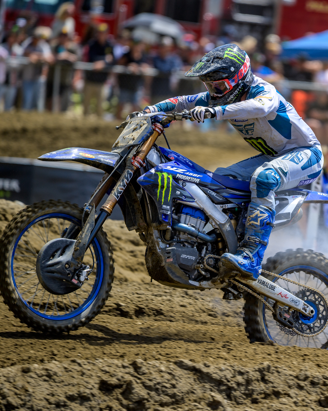 Motocross rider Cooper Webb on a dirt bike with Monster Energy branding on a muddy track.