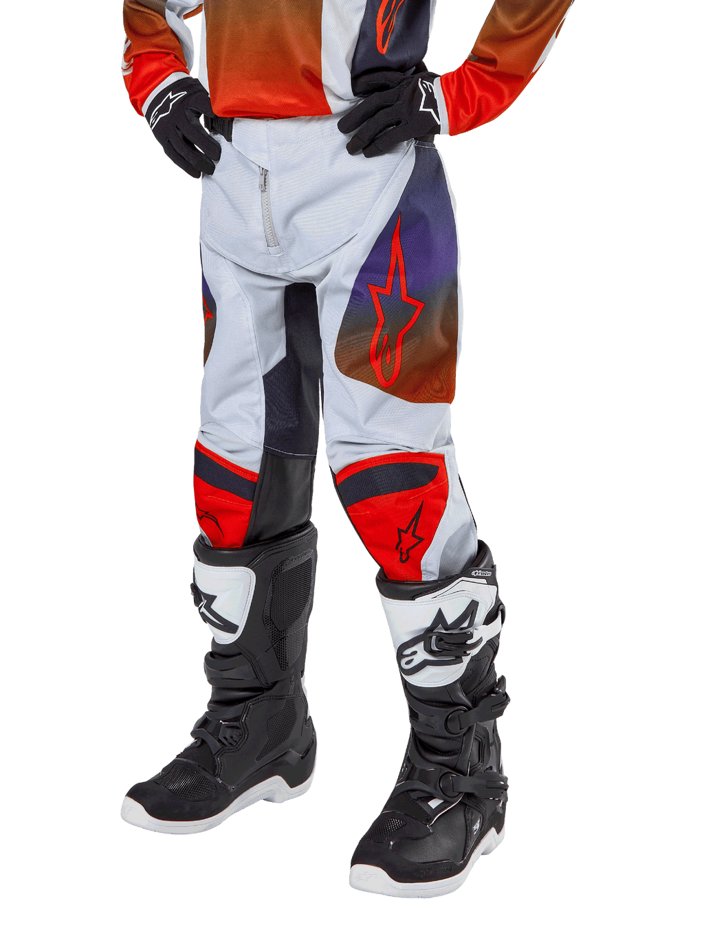 Alpinestars 2024 Youth Racer Hoen bukser, motocross-bukser til unge, lysegrå med Hot Orange og sorte detaljer, røde stjernelogoer på lårene og røde knæpaneler, båret med sort-hvide støvler, holdbart design til off-road kørsel