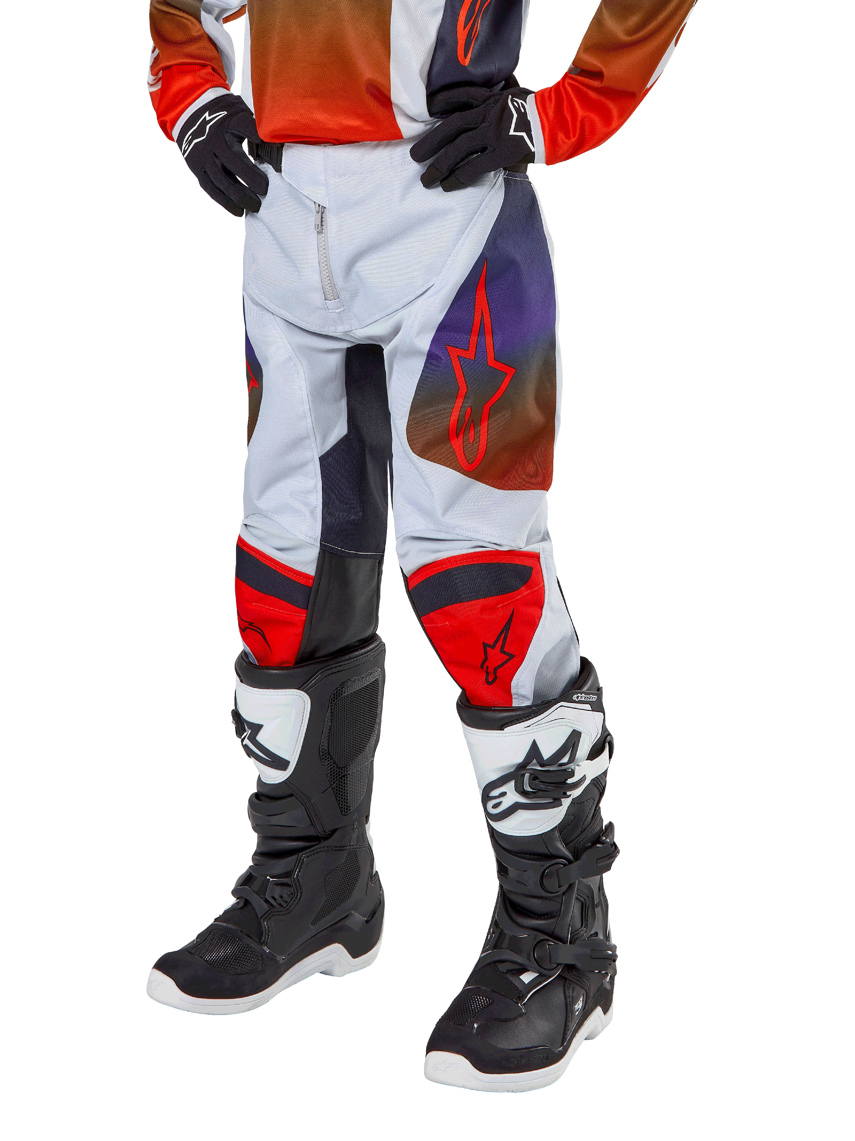 Alpinestars 2024 Youth Racer Hoen bukser, motocross-bukser til unge, lysegrå med Hot Orange og sorte detaljer, røde stjernelogoer på lårene og røde knæpaneler, båret med sort-hvide støvler, holdbart design til off-road kørsel