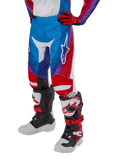 Alpinestars Youth 2024 Racer Pneuma bukser, motocrossbukser, blå, rød og hvid, båret med matchende handsker og støvler, hvidt stjernelogo på låret, sporty design til terrænkørsel