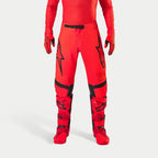 Alpinestars Supertech Ember LE bukser, motocrossbukser, rød fluo og lys rød med sorte detaljer, markante sorte stjernelogoer på lårene, sort taljespænde og knæpaneler, båret med matchende røde støvler og handsker for et koordineret racersæt.