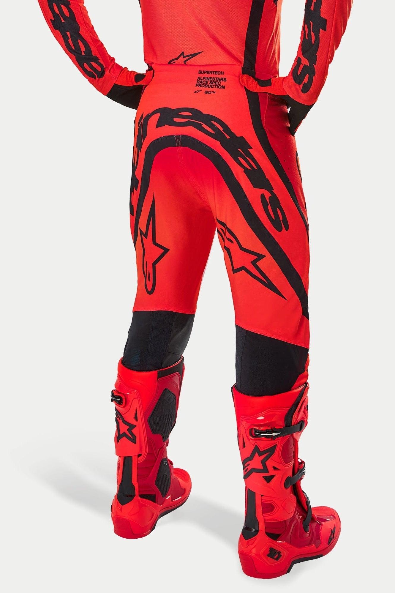 Alpinestars Supertech Ember LE bukser, motocrossbukser, fluorød, lys rød og sort, set bagfra med stort sort branding på bagen og stjernelogoer, bæres med matchende røde motocrossstøvler, professionelt racerudstyr til terrænkørsel